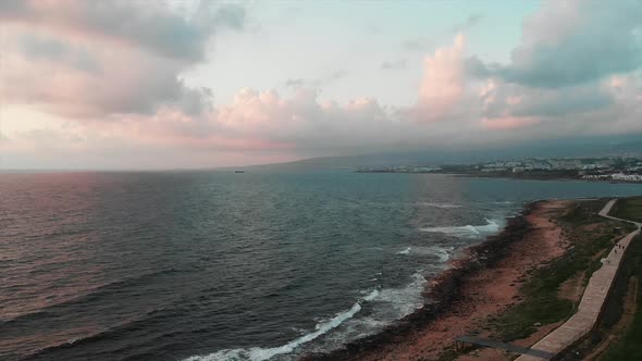 Aerial drone view of rocky beach with small pedestrian quay and big waves that bump into cliffs