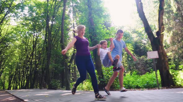 A Family of Three Runs Along an Alley in the Park