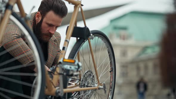 Man Checking Wheels on Bike