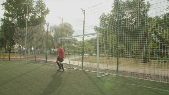 Soccer Goalkeeper Making Diving Save on Football Pitch at Daybreak