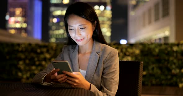 Business woman using smart phone in city at night 