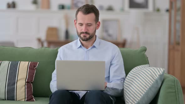 Young Man Working on Laptop on Sofa 