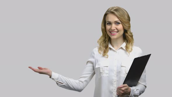 Happy Young Woman with Clipboard Raises Her Right Palm Up