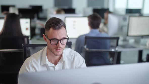 Portrait of Young Entrepreneur in Open Space Office Working on Decktop Computer