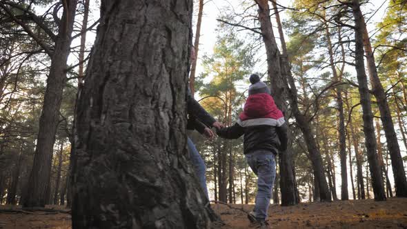 Young Mother Walking with a Little Son in Autumn Forest.