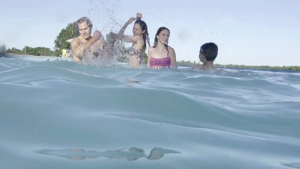 Family in swimming pool splashing each other