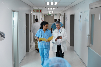Diverse male and female doctors walking through hospital corridor discussing / Photodune, Misc