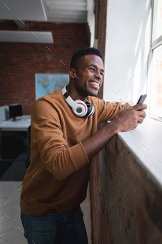 African american businessman standing in office with head phones off having video call on smartphone / Photodune, Misc