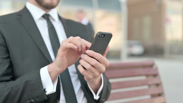 Close Up of Businessman Using Smartphone While Sitting Outdoor on Bench