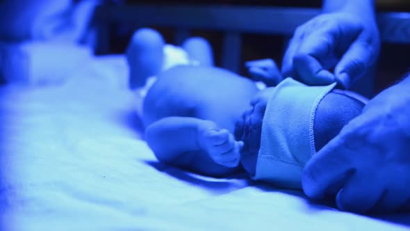 Newborn Having a Treatment for Jaundice Under Ultraviolet Lamp in Home Bed