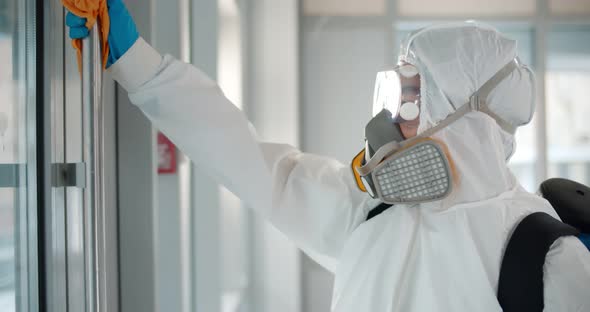 Health Worker in Protective Clothing Disinfecting Creative Office