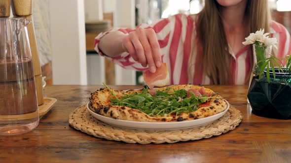 Chef in the Pizzeria Prepares a Pizza and Decorates It with Prosciutto