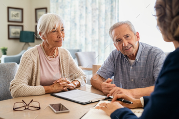 ealth insurance at home. Old couple planning their investments with financial advisor after retirement at home. Aged couple consulting with insurance agent while sitting together with prospectus at home.