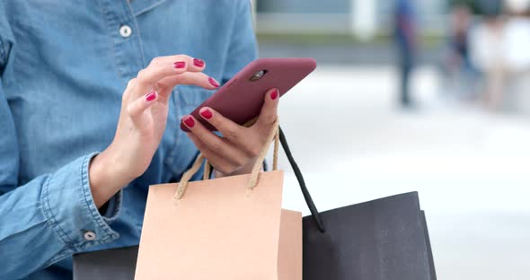 Woman use of mobile phone for shopping with holding shopping bag