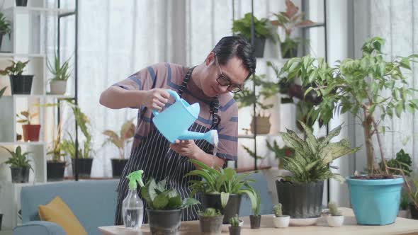 Asian Man Holding Watering Pot To Water The Plants At Home