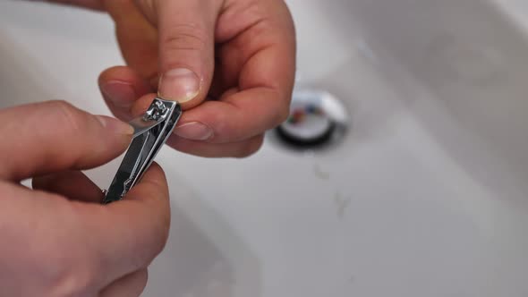 A Young Man Cuts His Nails Over the Sink