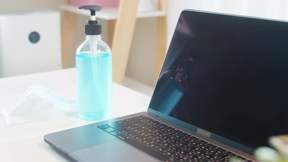 Hand sanitizer gel for hand hygiene corona virus protection with tablet, laptop at home.