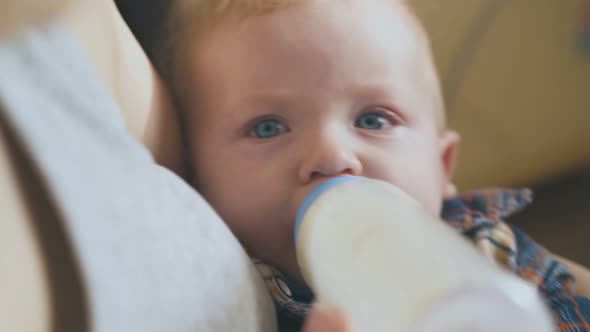 Mother Feeds Little Baby with Tasty Milk Mix in Light Room