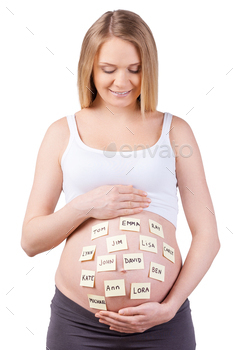  looking at the adhesive notes with baby names and smiling while standing isolated on white