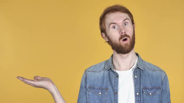 Redhead Man Showing Product at Side Yellow Background