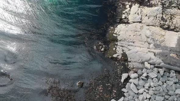 Topdown reveal shot of blue water rocky beach