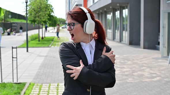 Caucasian Business Woman in a Suit Listening to Music with Headphones and Singing Along to Dance