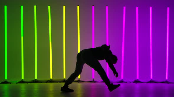 Professional Breakdancer Performs Complex Spins on the Floor. Silhouette of a Man Dancing Against