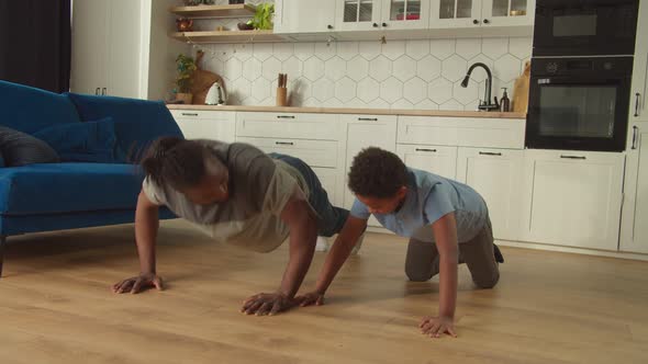 Active African American Father and Cute Son Doing Push Ups Exercise at Home
