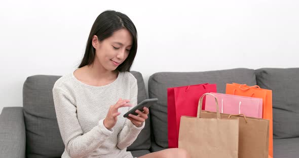 Woman Using Mobile Phone for Online Shopping with Lots of Paper Bag at Home