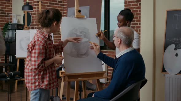 Teacher and Student Helping Old Man to Draw Vase on Canvas