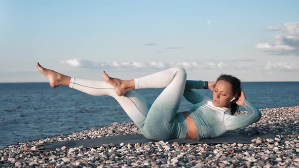 Fitness Lady Lying on Pebble Sea Coast Training Abs Muscle Enjoying Outdoor Physical Activity