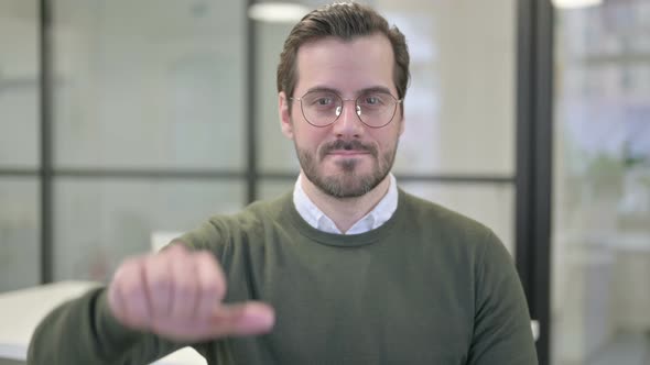 Portrait of Young Businessman Showing Thumbs Down Gesture