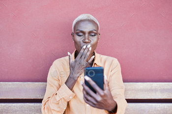 Beautiful mature african woman sitting outdoor while sending kisses on a video call / Photodune, Misc