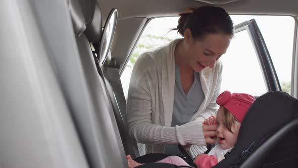 Caucasian mother keeping her baby in safety seat in the car