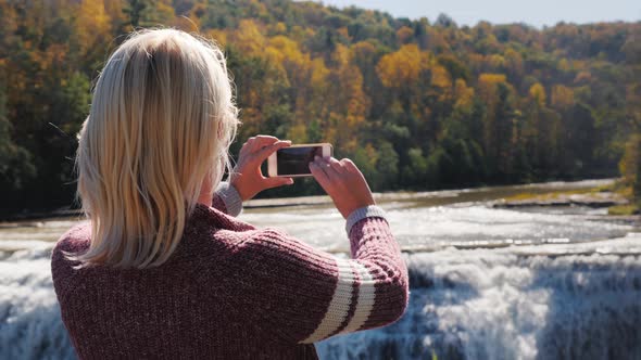 A Woman Is Taking a Picture of a Waterfall in Letchworth State Park