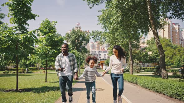 Friendly African Ethnicity Family Runs Along the Path of the City Park