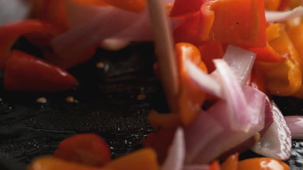 Stir frying onion and orange and red bell pepper. Slow Motion.