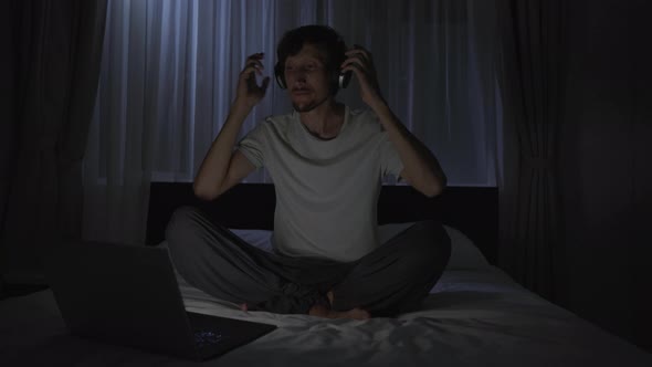 A Man at Night Turns on a Meditation Relaxation Application on His Computer to Relax Before Going to