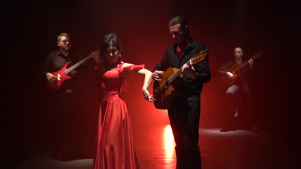 Flamenco Dance Performed By a Professional Girl Next To Playing Guitarists Music. Light From Behind