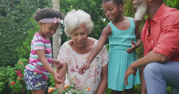 Happy senior african american grandparents with grandchildren working in garden