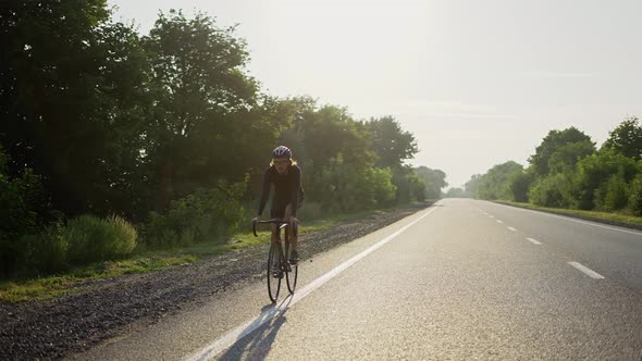 Male Cyclist in Helmet Rides Bicycle Along an Empty Track