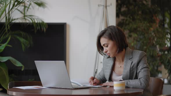 Woman Working From Home Using Laptop Computer While Reading Text Message