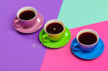 Colorful coffee cups and saucers on colorful vibrant background / Photodune