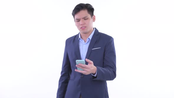 Stressed Young Asian Businessman Using Phone and Getting Bad News