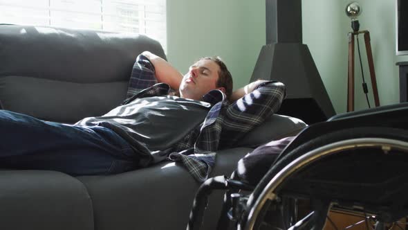 Relaxed caucasian disabled man lying on sofa in living room