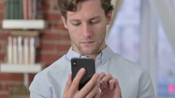 Focused Portrait of Young Man Using Phone