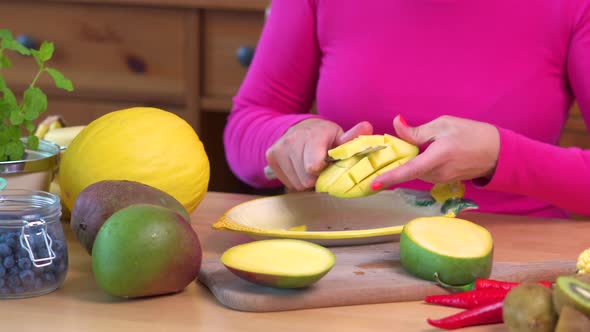 Woman in a Pink Blouse Chopping a Juicy Yellow Mango 