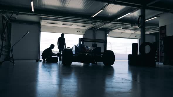 Servicemen are Repairing a Racing Car in a Garage