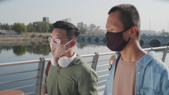 Two Asian Friends in Face Masks Chatting during Walk