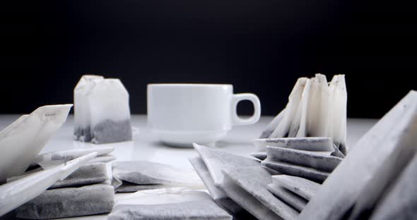 Super Closeup Set of Tea Bags on a White Table on a Black Background and a White Cup of Tea